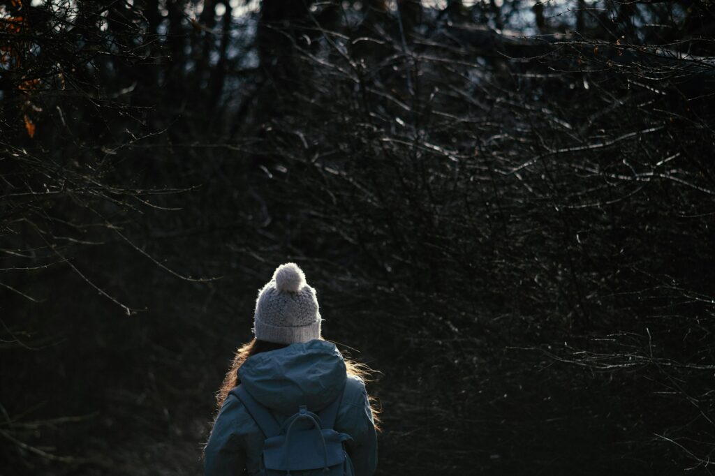 Woman walking through the woods in early morning light.